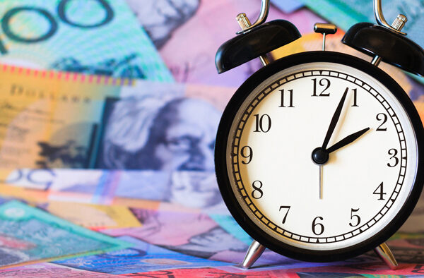 An alarm clock reading 2:04 sits with a background of blurred Australian money