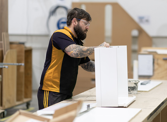 A man in a warehouse building a cabinet drawer